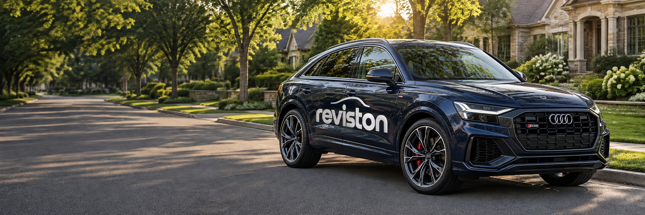 A navy Audi SQ8 with white Reviston Signature branding on a sunlit neighborhood street
